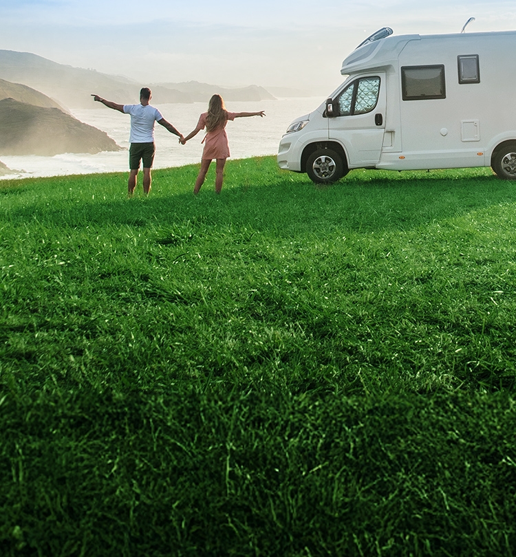 Camping-Szene mit Wohnmobil und Paar in Landschaft am Meer