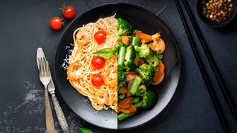 Ein Teller, aufgeteilt in eine Hälfte mit Garnelennudeln mit Tomaten und Basilikum und auf der anderen Seite mit gebratenem Gemüse mit Brokkoli und Karotten.