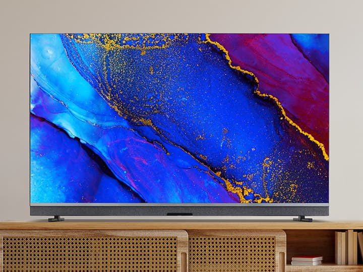 Ein moderner Fernseher auf einer Holzkonsole, der ein lebendiges abstraktes Bild in den Farben Blau, Rot und Gold anzeigt.