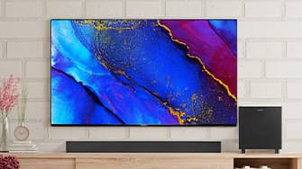 Ein Flachbildfernseher mit lebendiger abstrakter Kunst in Blau-, Rot- und Gelbtönen, der an einer Ziegelwand über einer Holzkonsole angebracht ist.