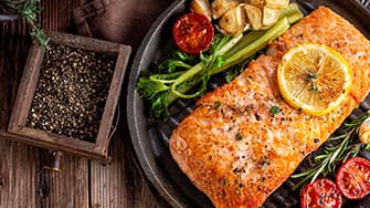 Knusprige Hähnchenflügel mit Glasur und Frühlingszwiebeln auf Teller – zubereitet in der MEDION Heißluftfritteuse.