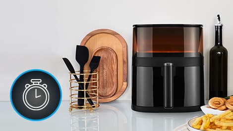 Küchenarbeitsplatte mit Heißluftfritteuse, Besteckhalter, Holztablett und Olivenölflasche. Links ist ein Stoppuhr-Symbol zu sehen.