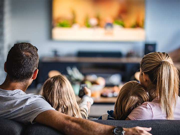 Familie sitzt auf dem Sofa und schaut TV