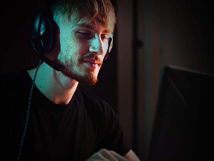 Person beim Gaming mit Headset in dunkler Gaming-Umgebung