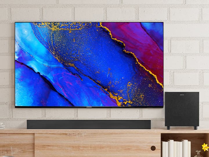 Ein Flachbildfernseher mit lebendiger abstrakter Kunst in Blau-, Rot- und Gelbtönen, der an einer Ziegelwand über einer Holzkonsole angebracht ist.