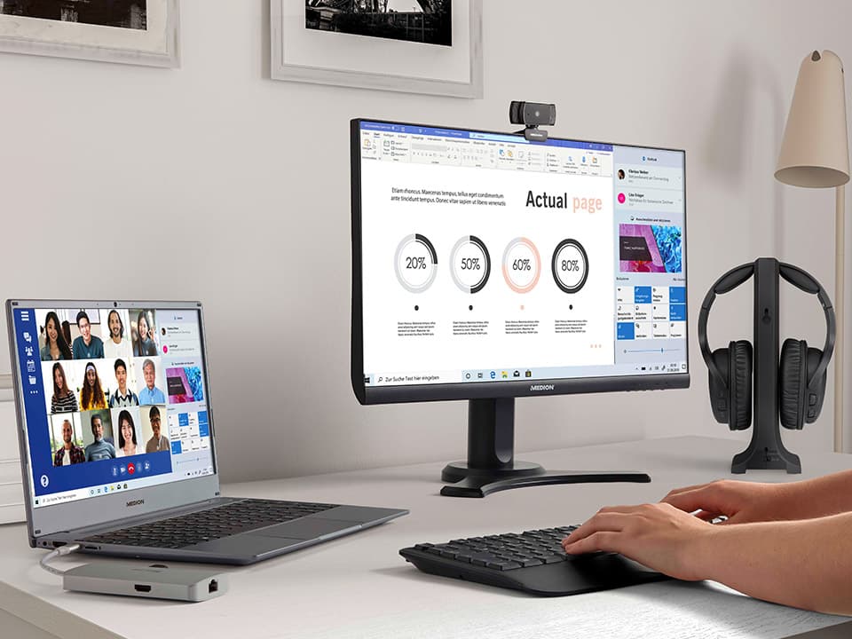 Großer Bildschirm mit Office-Anwendungen und Videokonferenz am Homeoffice-Arbeitsplatz mit Laptop und Zubehör.