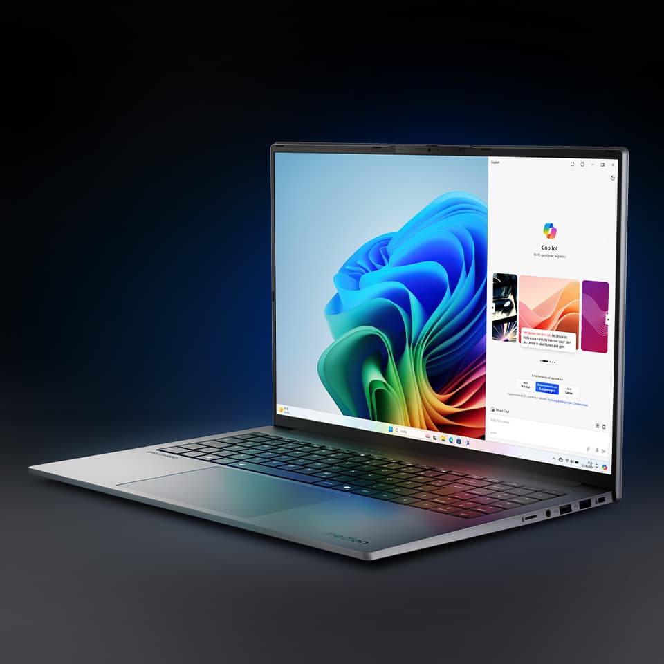 Ein schräg nach rechts gedrehter aufgeklappter Laptop auf einem grauen Hintergrund. Das Display zeigt einen Copilot Screen.