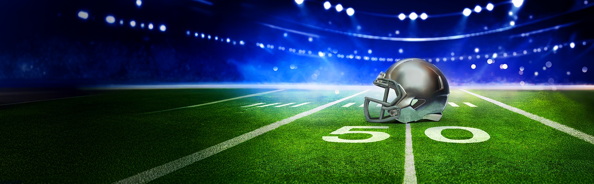 American-Football-Feld im Stadion bei Flutlicht mit Football-Helm auf der 50-Yard-Linie