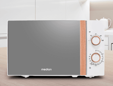 MEDION Mikrowelle mit Holz-Akzent in moderner weißer Küche auf einer Arbeitsplatte.