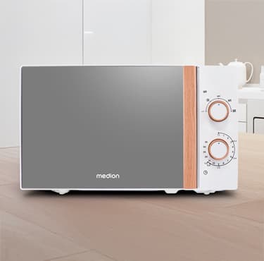 Weiße Mikrowelle mit reflektierender Tür und Holzelementen an den Drehknöpfen, platziert auf einer Holzarbeitsplatte in einer modernen Küche.