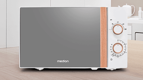 Weiße Mikrowelle mit reflektierender Tür und Holzelementen an den Drehknöpfen, platziert auf einer Holzarbeitsplatte in einer modernen Küche.