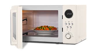 Weiße Mikrowelle mit offener Tür, in der sich ein Teller mit gemischtem Gemüse und Fleisch befindet. Die Digitaluhr zeigt 12:00 Uhr.