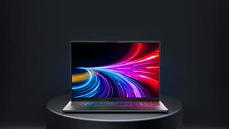 Aufgeklapptes von vorne zu sehendes Laptop auf einem runden grauen Podest. Auf dem Display sind neonfarbene Laserstrahlen zu sehen.