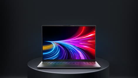 Aufgeklapptes von vorne zu sehendes Laptop auf einem runden grauen Podest. Auf dem Display sind neonfarbene Laserstrahlen zu sehen.